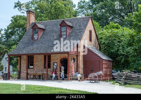 Zwei Soldaten unterhalten sich vor einem Backsteinhaus im Magazinhof von Colonial Williamsburg, Virginia, USA. Stockfoto