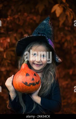 Halloween. Das Mädchen lacht und hält einen Kürbis in den Händen. Stockfoto