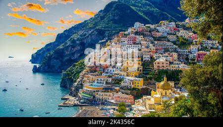 Luftaufnahme von Positano in Italien mit einem spektakulären Hintergrund aus goldenen Wolken und bunten Häusern an der Küste Stockfoto