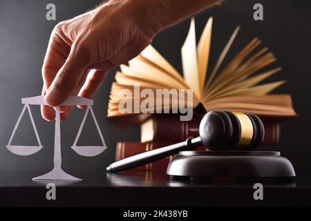Justizkonzept mit Keule, Gesetzen und Hand mit Skalenausschnitt auf schwarzem Hintergrund. Vorderansicht. Stockfoto