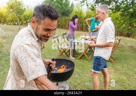 Die Leute um den Grill lächeln glücklich und lachen zusammen. Joy-Konzept. Stockfoto