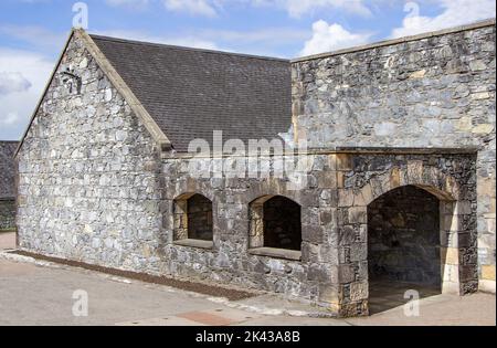 Altes Steingebäude mit Schieferdach, offenen Fenstern und einem großen gewölbten Eingang Stockfoto