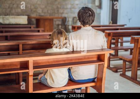 Christian Papa erzählt seinem Sohn biblische Geschichten über Jesus in kirk sitzen. Glaube, Religionsunterricht, moderne Kirche, Vatertag, väterliche Stockfoto