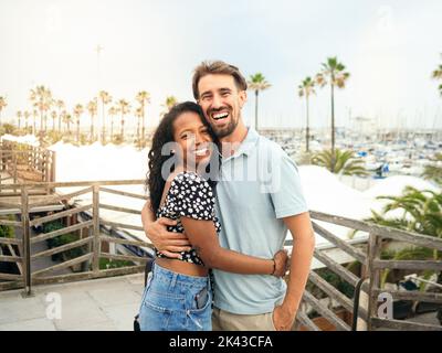 Happy diverse lächelnde heterosexuelle junge Paar Blick auf die Kamera während des Urlaubs. Glückliches Paar, Flitterwochen, Urlaub Stockfoto