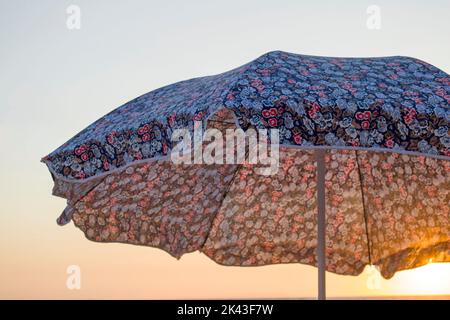 Sonnenschirm mit Blumenmuster während des Sonnenuntergangs. Stockfoto