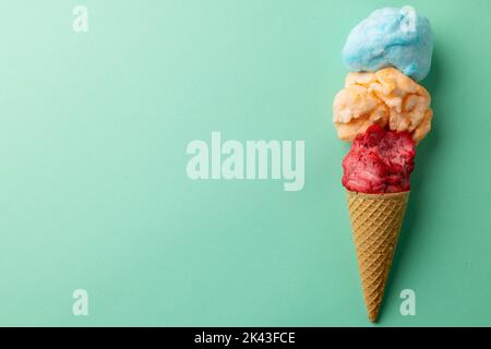 Horizontales Bild von drei farbigen Geschmacksrichtungen von Eis in Kegel, auf blauem Hintergrund mit Kopierraum Stockfoto