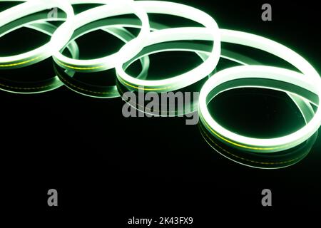 Bild von lebendigen spiralförmigen grünen Neonlicht klebt über schwarzem Hintergrund mit Kopierraum Stockfoto