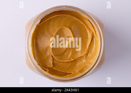 Bild eines Glases mit Erdnussbutter auf weißer Oberfläche Stockfoto