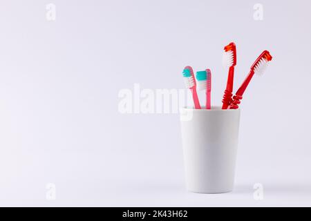 Bild von Zahnbürsten in Tasse auf grauem Hintergrund Stockfoto