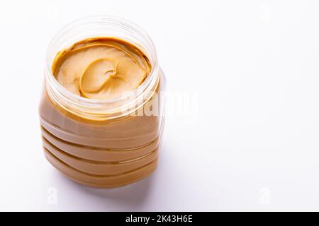 Bild eines Glases mit Erdnussbutter auf weißer Oberfläche Stockfoto