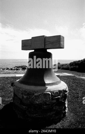 Eine Nebelglocke, die zu einem Denkmal konvergiert ist, ruht auf dem Rasen am Nubble Lighthouse, wo die Familie ein Foto auf den Felsen macht - Cape Neddick, Maine. Das imag Stockfoto