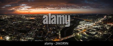 Panorama-Luftaufnahme des Sonnenuntergangs über den Lichtern aus dem Stadtgitter Stockfoto