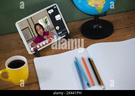 Biracial Grundschüler während der Klasse auf Tablet-Bildschirm. Kommunikationstechnik und Online-Bildung, digitale Composite-Bild. Stockfoto