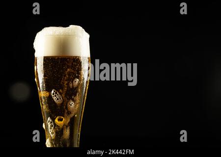 Bild eines vollen Bierglases mit Schaumbier, mit Platz für Kopien auf schwarzem Hintergrund Stockfoto