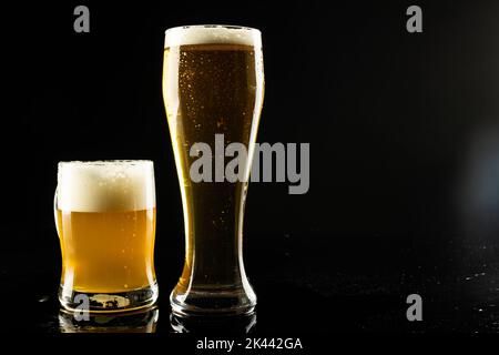 Bild von Vollpint Glas und Tankard von schaumigem Bier, mit Kopierraum auf schwarzem Hintergrund Stockfoto