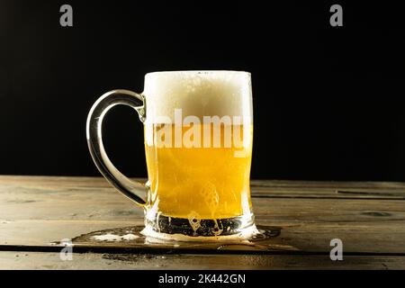 Bild von Glas-Tankard voll von schaumigem Bier auf Holztisch, mit Kopieplatz Stockfoto