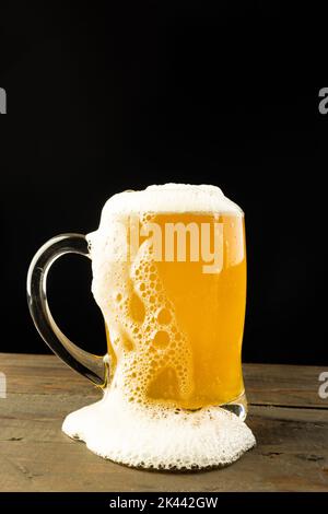 Bild von Glas-Tankard voll von schaumigem Bier auf Holztisch, mit Kopieplatz Stockfoto