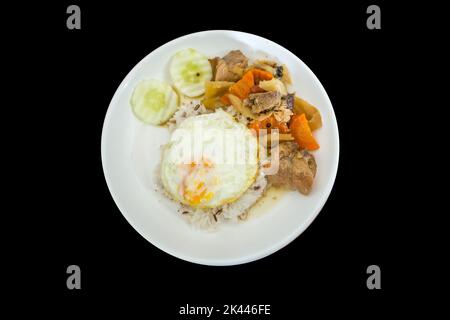 Stempelschnitt von geschrobenem Schwein über Reis und gebratenen Eiern auf schwarz isoliert. Stockfoto