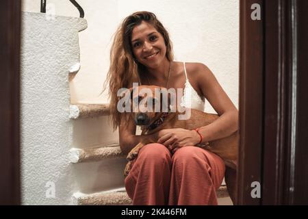 Porträt der schönen Latina Frau umarmt ihren Hund beide Blick auf die Kamera. Liebe für Tiere. Stockfoto