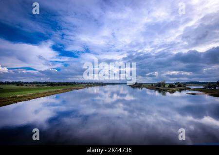 PRODUKTION - 27. September 2022, Mecklenburg-Vorpommern, Dömitz: Wolken spiegeln sich im glatten Wasser der Elbe nahe der Elbbrücke. Eine Biosphärenwoche feiert das 25.-jährige Jubiläum des UNESCO-Biosphärenreservats Elbe. Die Elblandschaft umfasst 278.660 Hektar. Am 30. September 2022 feiern die fünf Anrainerstaaten das Jubiläum. Foto: Jens Büttner/dpa Stockfoto