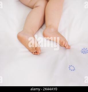 Das Bild der Unschuld. Ein zugeschnittenes Bild eines Babys, das auf einem Bett liegt. Stockfoto