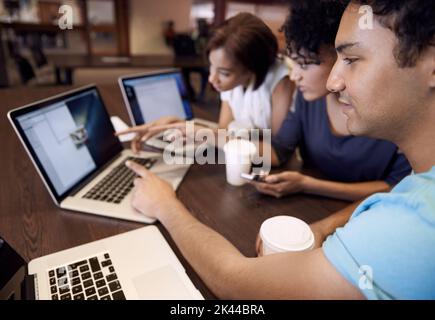 Dynamik der Studiengruppe. Eine Gruppe von Studenten, die einen Laptop verwenden, um eine Gruppenaufgabe abzuschließen. Stockfoto