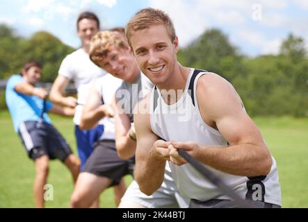 Lassen Sie uns das gemeinsam tun. Eine Gruppe junger Männer, die an einem Tauziehen teilnehmen. Stockfoto