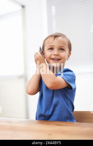 Oma anrufen. Ein netter kleiner Junge, der auf einem Handy spricht. Stockfoto