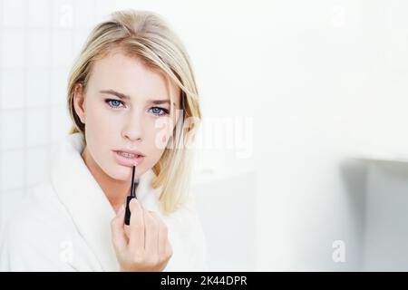 Feuchtigkeit für die Lippen. Eine schöne junge Frau, die Lipgloss anwendet. Stockfoto