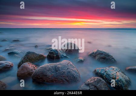 Farbenfroher Herbstuntergang an der Küste mit nassen Felsen und Meeresbrandung am Botnerbaugen in Larkollen, auf der Ostseite des Oslofjord, Østfold fylke, Norwegen. Stockfoto