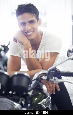 Hes hat den Biker heruntergeschaut. Ein hübscher junger Mann, der auf seinem Motorrad sitzt. Stockfoto