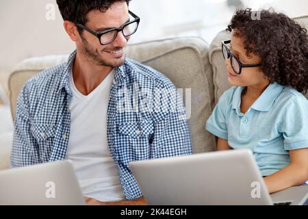 Vater zeigen, wie es funktioniert. Ein kleiner Junge und sein Vater arbeiten an Laptops. Stockfoto