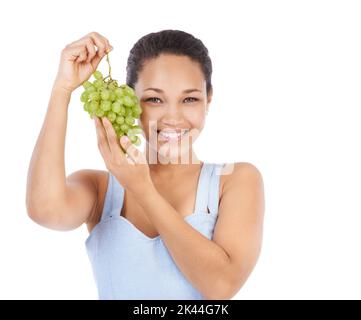 Ihre Lieblingsfrucht bei weitem. Junge Frau lächelt, während sie ein Traubenbündel hochhält - isoliert auf Weiß. Stockfoto