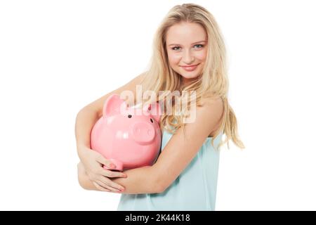 Kümmert sich um ihr Geld. Eine hübsche junge Frau umarmt ihr Sparschwein, während sie auf weißem Hintergrund isoliert ist. Stockfoto