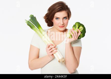 Eine gesunde Gewohnheit ist wichtig. Hübsche Brünette Frau hält einige gesunde Gemüse, während isoliert auf weiß. Stockfoto