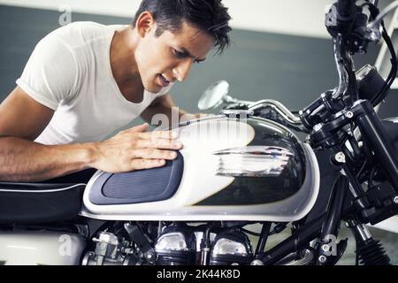 Kümmert sich um mein Baby... Ein hübscher junger Mann bewundert sein Motorrad. Stockfoto