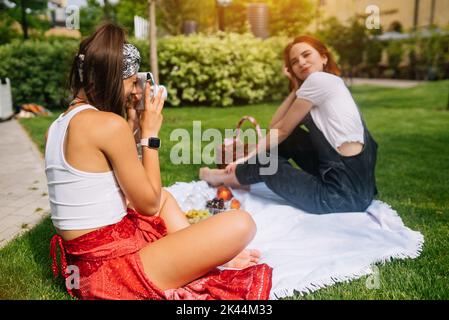 Cool junge Brünette Frau macht Foto von Freundin mit Kamera Stockfoto