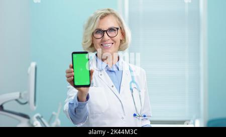 Der Arzt zeigt die Analyseergebnisse, indem er das Telefon in der Hand hält Stockfoto