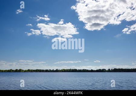 Wunderschöne Flusslandschaft. Lake Surface an einem sonnigen perfekten Tag. Die Oberfläche des Wassers vor dem Hintergrund von Bäumen und einem blauen Himmel. Verschwommenes Bild Stockfoto