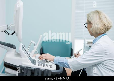Der Arzt hält eine Ultraschallsonde, die das Geschlecht des Babys bestimmt Stockfoto