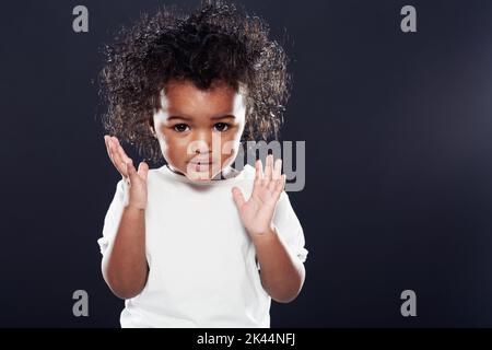 Wenn Sie glücklich sind und Sie es wissen ... klatschen Sie in die Hände. Ein nettes Mädchen auf schwarzem Hintergrund. Stockfoto