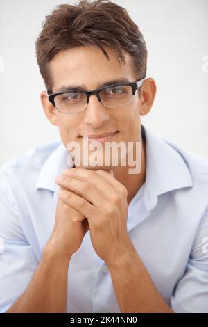 Handlich UND intelligent. Porträt eines hübschen jungen Geschäftsmannes, der eine Brille trägt und die Kamera anlächelt. Stockfoto