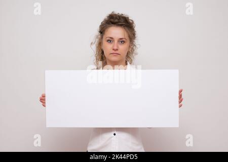 Hübsche Frau posiert hinter einem weißen Panel isoliert auf weißem Hintergrund Stock Foto Stockfoto