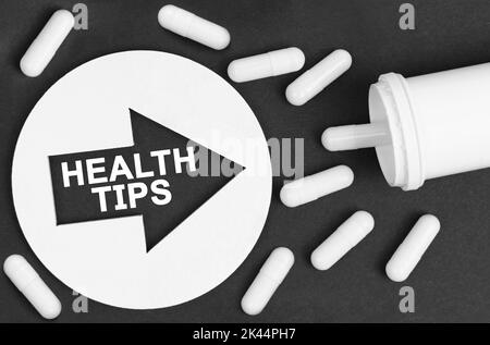 Medizinkonzept. Pillen auf schwarzem Hintergrund. Sie sind durch einen Kreis mit einem Pfeil gekennzeichnet, in dem es steht - GESUNDHEITSTIPPS Stockfoto