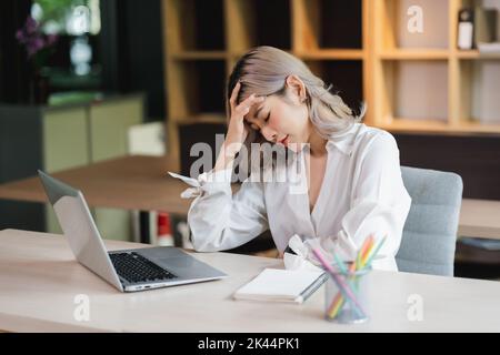 Gestresste asiatische Geschäftsfrau fühlt sich unbequem Arbeit Kopfschmerzen unglücklich Problem Arbeitnehmer Stockfoto