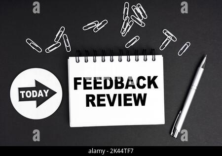 Geschäftskonzept. Auf schwarzem Hintergrund eine runde Platte - Today und ein Notizbuch mit der Aufschrift - FEEDBACK-REVIEW Stockfoto