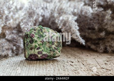 Eclogitgestein mit grünem Pyroxen und rotem Granat oder Pyrop auf natürlichem Holzhintergrund mit Kopierraum Stockfoto