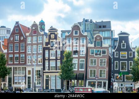 Niederlande. Fassaden typischer Gebäude in einer Sommerstraße in Amsterdam. Berühmtes schräges Haus Stockfoto