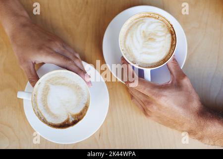 Kaffee-Kunst. Beschnittenes Bild von zwei Händen der Völker, die Cappuccinos halten. Stockfoto