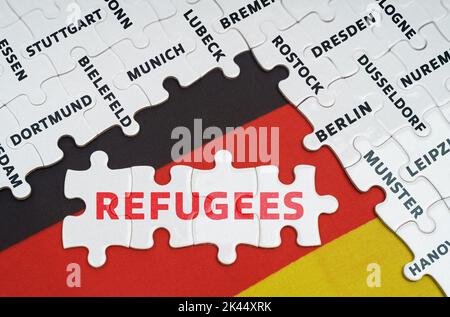 Nationales Konzept. Auf der Flagge Deutschlands gibt es Rätsel mit den Namen der Städte und Rätsel mit der Aufschrift - Flüchtlinge Stockfoto